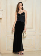 A woman wears Social Queen's 100% Silk Velvet & Tulle Mermaid Skirt with a cami top, strappy black heels, and a white purse, standing indoors by a cream wall and exuding vintage-inspired elegance.