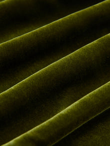 Close-up of green velvet fabric with parallel folds, showcasing the soft texture and vintage-inspired look of Social Queen's 100% Silk Velvet Wide-Leg Pants.