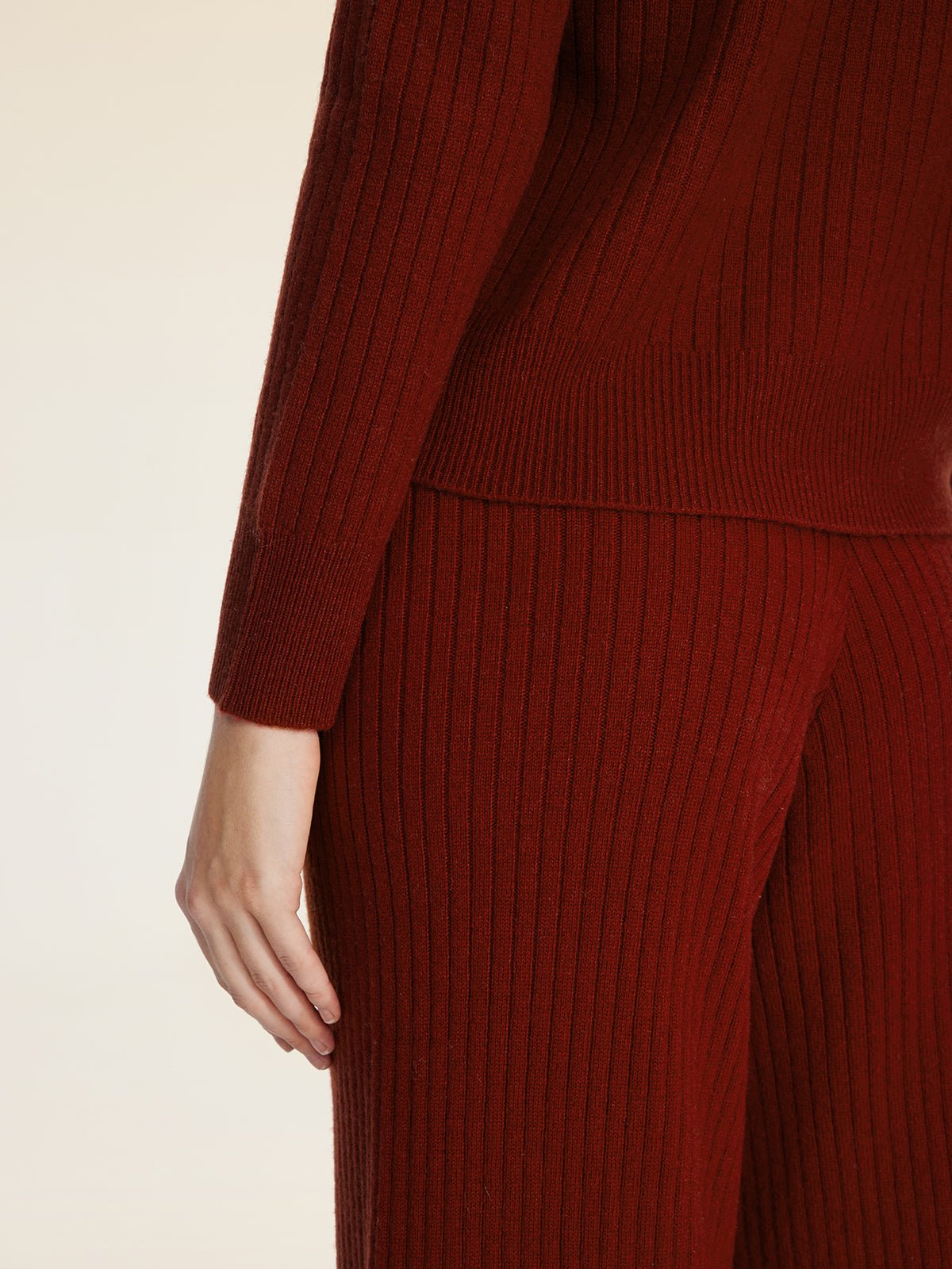 A person wears Social Queen's 100% Wool Knit Elastic Trousers in dark red, styled with a matching ribbed long-sleeve top. They're shown from shoulder to knee, one arm at their side, highlighting the trousers' straight-leg silhouette.