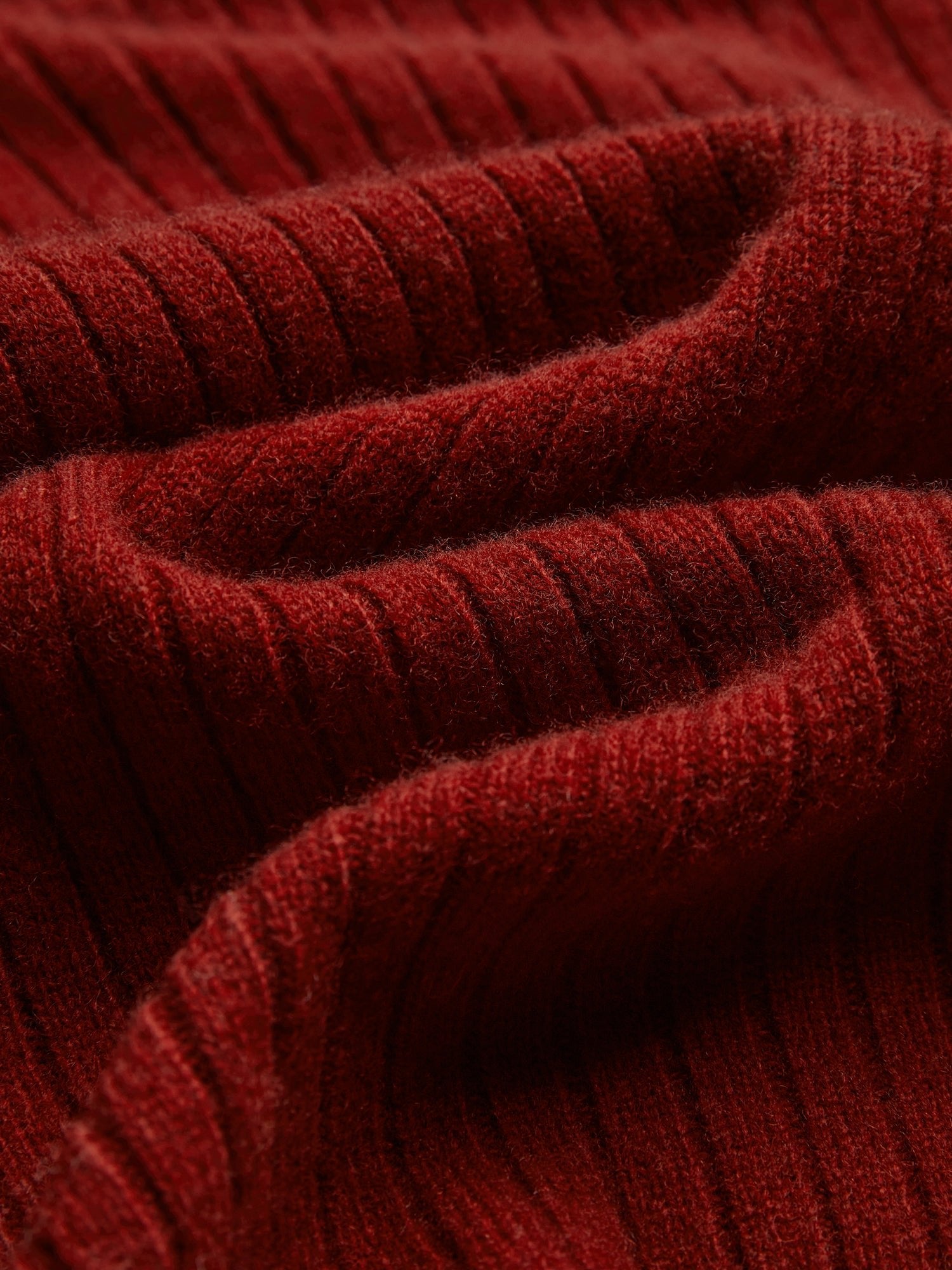 Close-up of the 100% Wool Knit Jacket by Social Queen, showcasing folded, ribbed red knit fabric with a visible, soft texture and wavy lines.