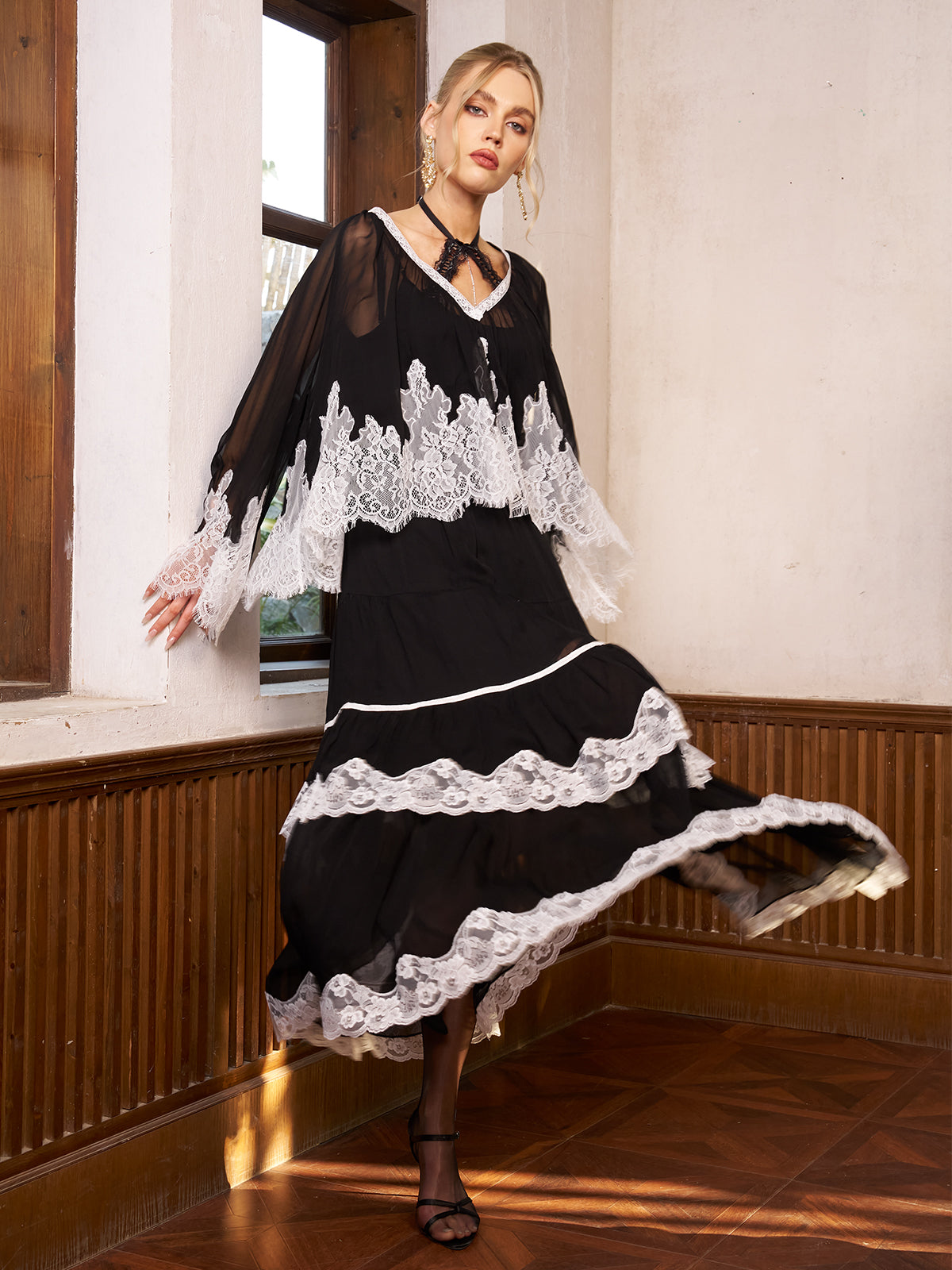 Woman wearing a black dress with white lace details in a room with wooden paneling.