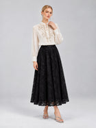 A woman stands against a plain gray background wearing the Social Queen Floral Vine Embroidered Blouse, paired with a long black lace skirt and silver sandals.