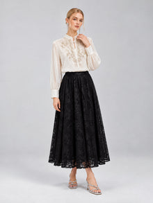 A woman stands against a plain gray background wearing the Social Queen Floral Vine Embroidered Blouse, paired with a long black lace skirt and silver sandals.