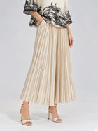 A woman models the Social Queen Striped Pleated Wide-Leg Pants, featuring subtle vertical stripes, paired with cream heeled sandals and a short-sleeve top with a black floral print. Her hands rest in the pants’ pockets against a plain grey background.