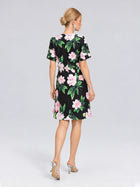 A woman with blonde hair in a bun is seen from behind wearing the Social Queen 3D Peony Floral Shift Dress, featuring a black base with pink peony prints, paired with silver high heels.