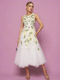 A woman poses against a pink background in the Social Queen 3D Daisy Embroidered Tulle Dress, styled with a small purse and strappy heels.