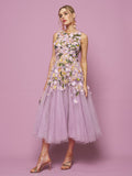 A woman stands against a lilac background in the Social Queen 3D Daisy Embroidered Tulle Dress, an A-line silhouette with sleeveless design and daisy details, paired with heeled sandals.