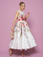 A woman poses against a pink background in the Social Queen 3D Floral Embellished Jacquard Gown, paired with a small purse and gold heels.