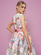 A woman in the Social Queen 3D Floral Embellished Jacquard Gown stands against a pink background, glancing over her shoulder.