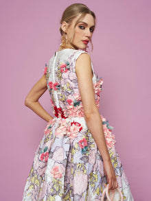 A woman in the Social Queen 3D Floral Embellished Jacquard Gown stands against a pink background, glancing over her shoulder.