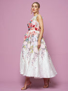 A woman poses against a pink background in the Social Queen 3D Floral Embellished Jacquard Gown, paired with metallic heels.