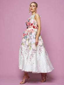 A woman poses against a pink background in the Social Queen 3D Floral Embellished Jacquard Gown, paired with metallic heels.