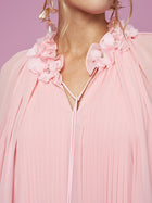 Close-up of a person wearing Social Queen's 3D Floral Embellished Silk Dress in light pink, featuring pleats and 3D floral details on the shoulders, styled with gold leaf earrings against a pink backdrop.