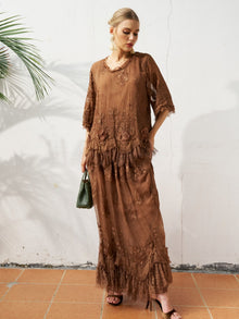 A woman stands against a white wall wearing the Social Queen 3D Floral Embroidered 100% Silk Ruffle Blouse, paired with a small green handbag and black heeled sandals.