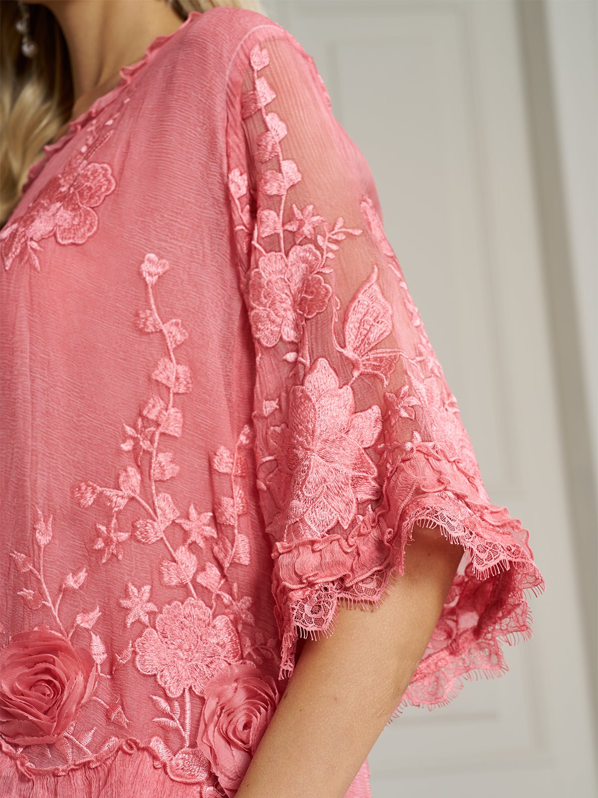 Close-up of a person in the Social Queen 3D Floral Embroidered 100% Silk Ruffle Blouse, featuring pink sheer fabric, lace details, and appliqué flowers on the sleeves and bodice.