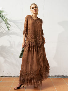 A woman stands against a white wall wearing the Social Queen 3D Floral Embroidered 100% Silk Ruffle Skirt, paired with black heels, hoop earrings, and holding a small green handbag.