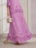 A person wears the Social Queen 3D Floral Embroidered 100% Silk Ruffle Skirt in lavender, paired with gold open-toe heels and a small handbag decorated with white flowers.
