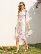 Woman in a Social Queen 3D Floral Embroidered Beaded Dress and sunglasses, carrying a matching handbag, strolls on grass by a white wall—a chic pick for wedding guests.