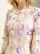 A woman wears the Social Queen 3D Floral Embroidered Beaded Dress, featuring intricate pastel purple, white, and yellow appliqué—an ideal wedding guest dress.