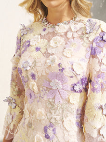 A woman wears the Social Queen 3D Floral Embroidered Beaded Dress, featuring intricate pastel purple, white, and yellow appliqué—an ideal wedding guest dress.