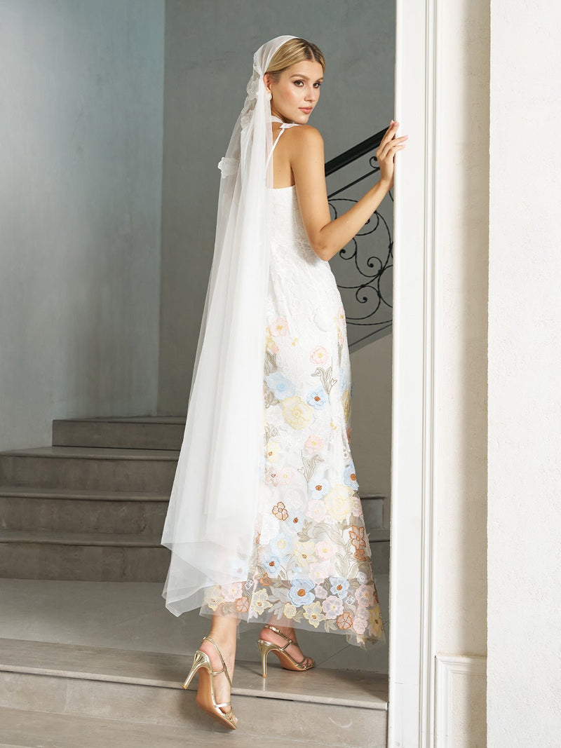 A woman in the Social Queen 3D Floral Embroidered Lace Strap Gown with Veil stands on stairs, looking back over her shoulder.