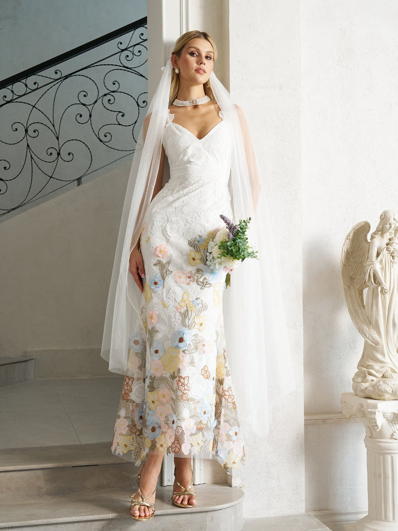 A woman wears the Social Queen 3D Floral Embroidered Lace Strap Gown with Veil, standing indoors by a staircase and holding a bouquet, elegantly showcasing this evening formal dress.