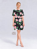 A woman poses against a plain backdrop wearing the Social Queen 3D Peony Floral Shift Dress in black, styled with silver heels, statement earrings, and a petite silver handbag.