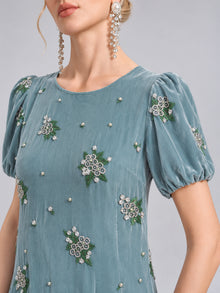 A woman wears the Social Queen Beaded Floral Silk Velvet Dress, featuring teal puff sleeves, luxurious silk-blend velvet, intricate beaded floral embroidery, and pearl embellishments. She completes the elegant look with long, dangling pearl earrings—an ideal choice for a sophisticated wedding dinner dress.
