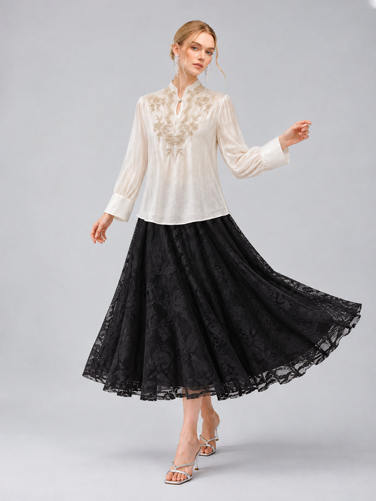 A woman models the Social Queen Floral Vine Embroidered Blouse in ivory, paired with a long black lace skirt featuring a relaxed straight silhouette, standing against a plain gray background.