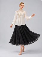 A woman models the Social Queen Floral Vine Embroidered Blouse in ivory, paired with a long black lace skirt featuring a relaxed straight silhouette, standing against a plain gray background.