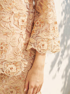 Close-up of a person wearing the Floral Embroidered Lace Top with Beaded Details by Social Queen, highlighting the intricate sleeve embroidery and delicate lace against a softly lit background.
