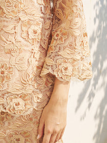 Close-up of a person wearing the Floral Embroidered Lace Top with Beaded Details by Social Queen, highlighting the intricate sleeve embroidery and delicate lace against a softly lit background.