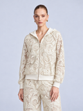 A woman wears a cream-colored, zip-up Paisley Embroidered Lace Hooded Jacket crafted from floral cutout lace.