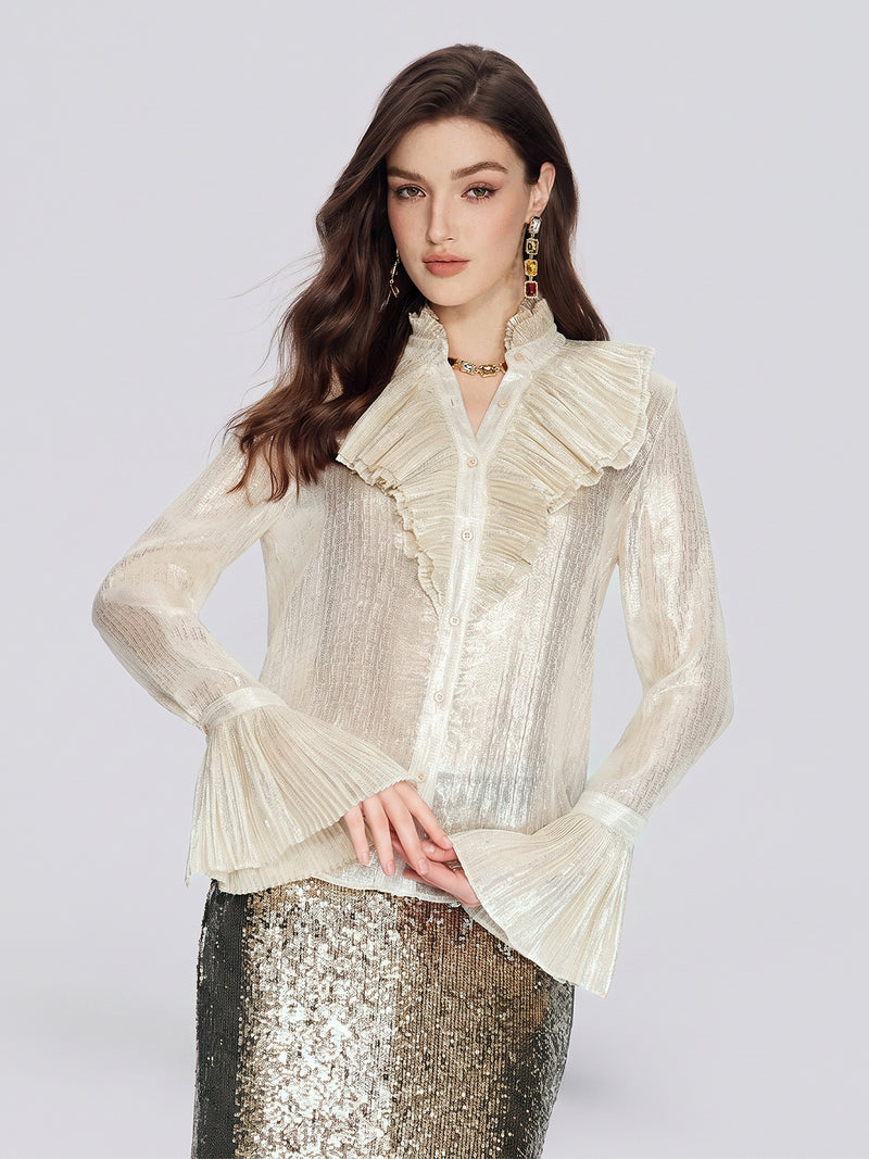 A woman stands facing forward against a plain light background, wearing the Social Queen Ethereal Metallic Ruffle Silk Blouse with a shimmery cream finish and a sequined skirt.