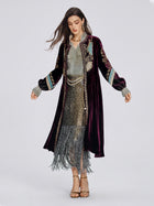 A woman wears the Handcrafted Embroidered Velvet Jacket by Social Queen over a beaded fringe dress, standing against a plain background.