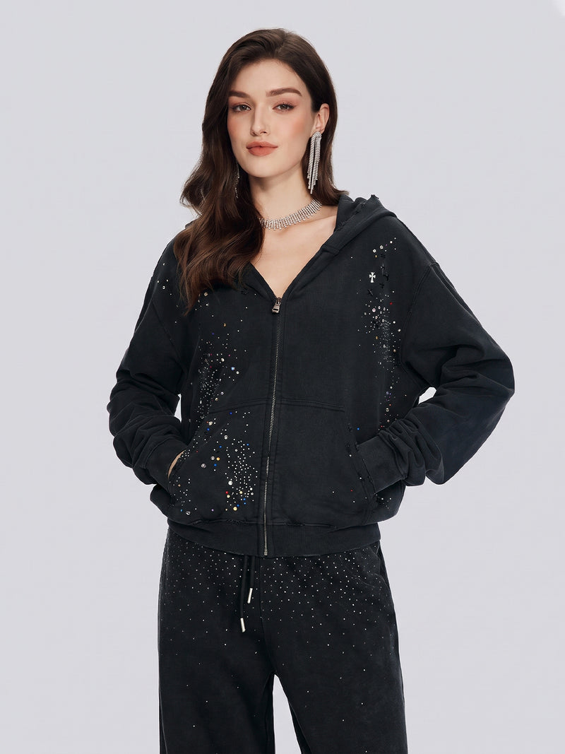 A woman wears the Social Queen Hand-Applied Rhinestone Washed Hoodie with matching pants, featuring small sparkling embellishments, while standing against a plain light background.