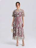 A woman stands facing forward against a plain light background, wearing the Social Queen Floral Beaded A-Line Dress, styled with open-toe heels and holding a small handbag.