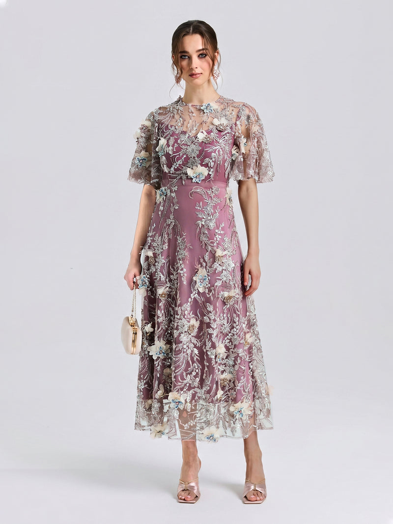 A woman stands facing forward against a plain light background, wearing the Social Queen Floral Beaded A-Line Dress, styled with open-toe heels and holding a small handbag.