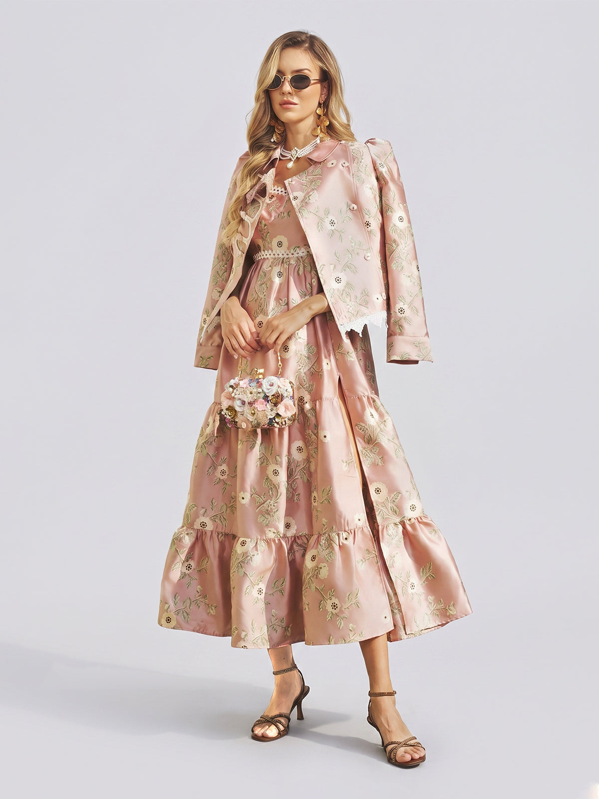 A woman wearing the Social Queen Embroidered Jacquard Ruffle Lace-Trim Dress with a matching jacket, accessorized with a small floral purse, sunglasses, and heeled sandals, stands against a plain light background.