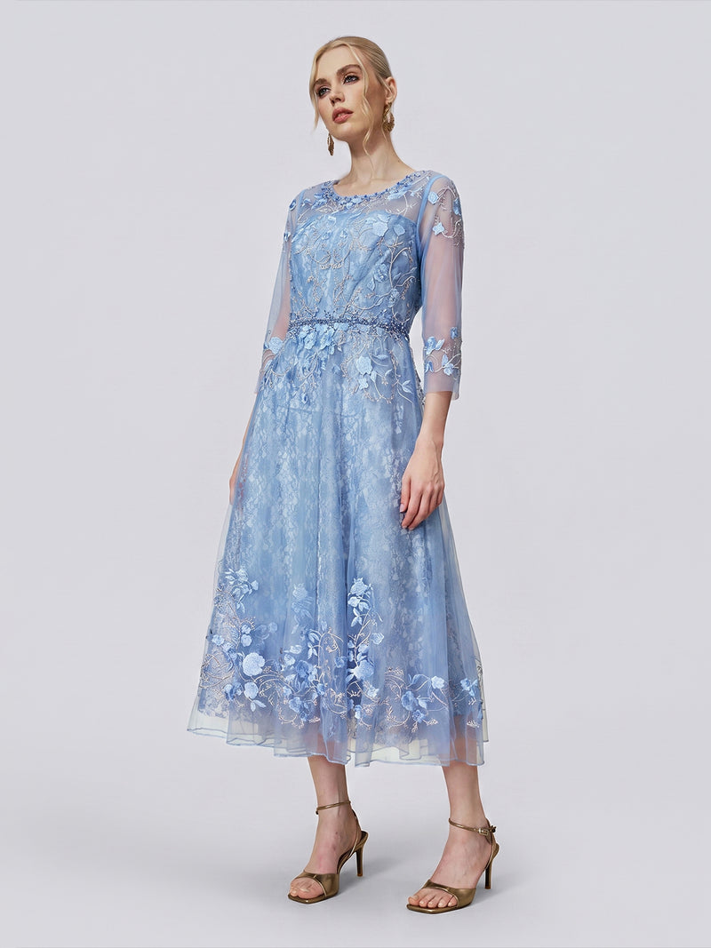 A woman stands in a neutral pose against a plain light background, wearing the Social Queen Beaded Floral Embroidered Mesh Dress—a light blue, long-sleeve, A-line midi dress featuring delicate floral embroidery and a sheer mesh overlay.