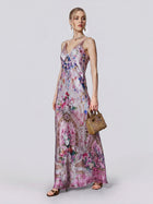 A woman wearing the Baroque Print Mulberry Silk Dress by Social Queen, styled with a small tan handbag, earrings, and sandals, stands against a plain light background.