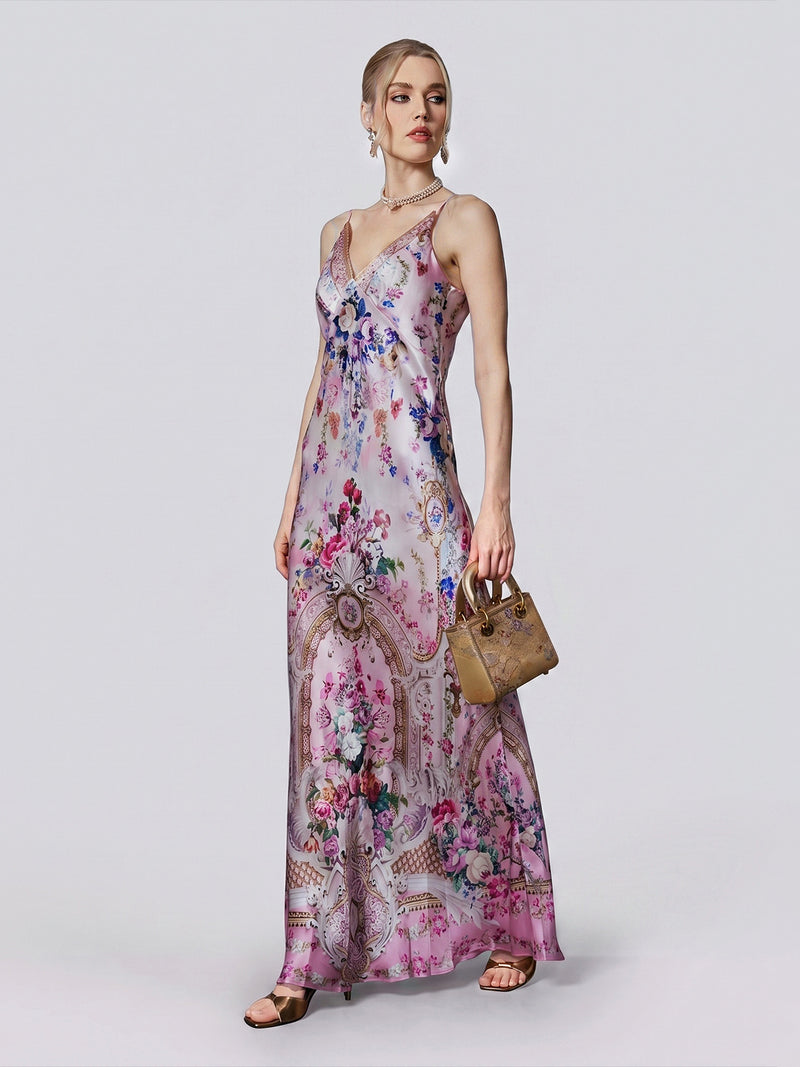 A woman wearing the Baroque Print Mulberry Silk Dress by Social Queen, styled with a small tan handbag, earrings, and sandals, stands against a plain light background.