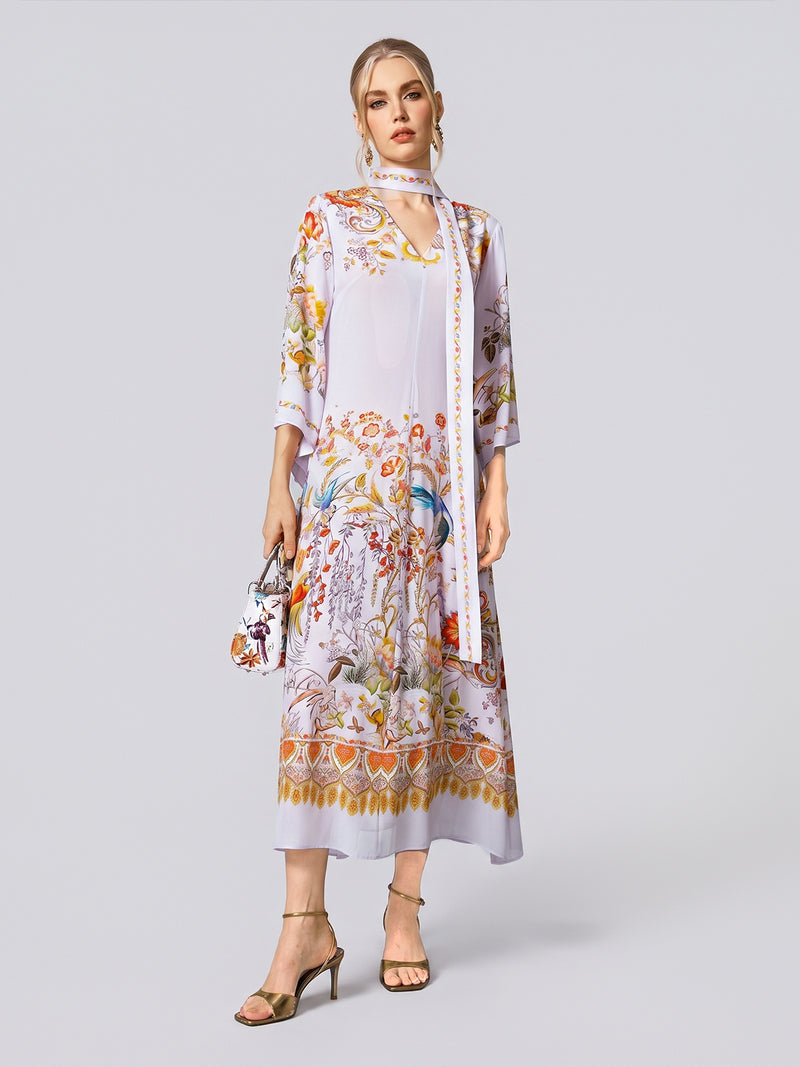 A woman wears the Social Queen Floral Bird Print Silk Dress with Scarf, featuring three-quarter sleeves and a delicate floral bird print, styled with the detachable scarf, a small purse, and beige heeled sandals against a plain background.