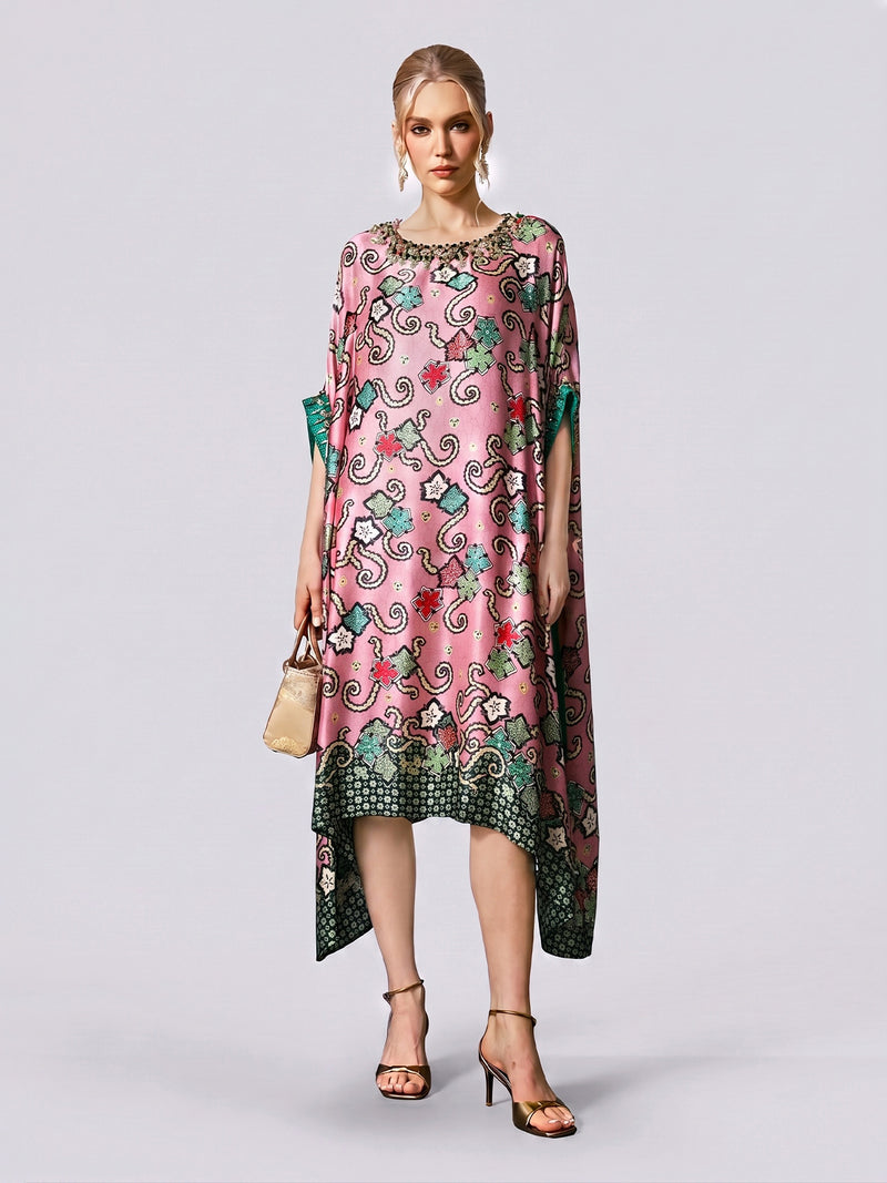 A woman stands against a plain light background wearing the Social Queen Beaded Printed Silk Kaftan Dress, paired with heeled sandals and a small handbag.
