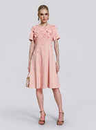 A woman models the Social Queen 3D Floral Appliqué A-Line Dress in light pink, featuring delicate 3D floral appliqués on the bodice and a knee-length A-line silhouette, while holding a small purse against a plain background.