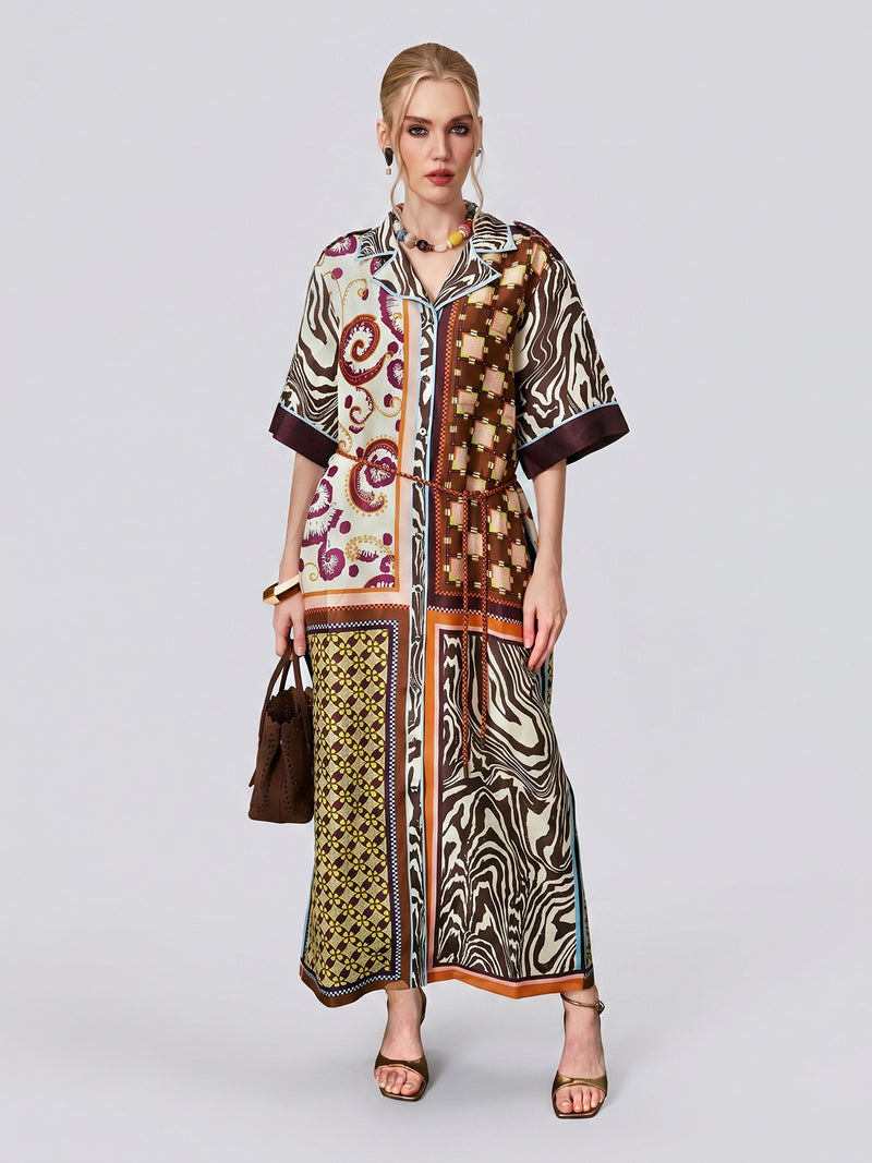 A woman wears the Social Queen Patchwork Print Cotton Shirt Dress, a loose, ankle-length dress featuring vintage patchwork and paisley motifs, styled with the included belt. She accessorizes with a brown handbag and heeled sandals while standing against a plain background.