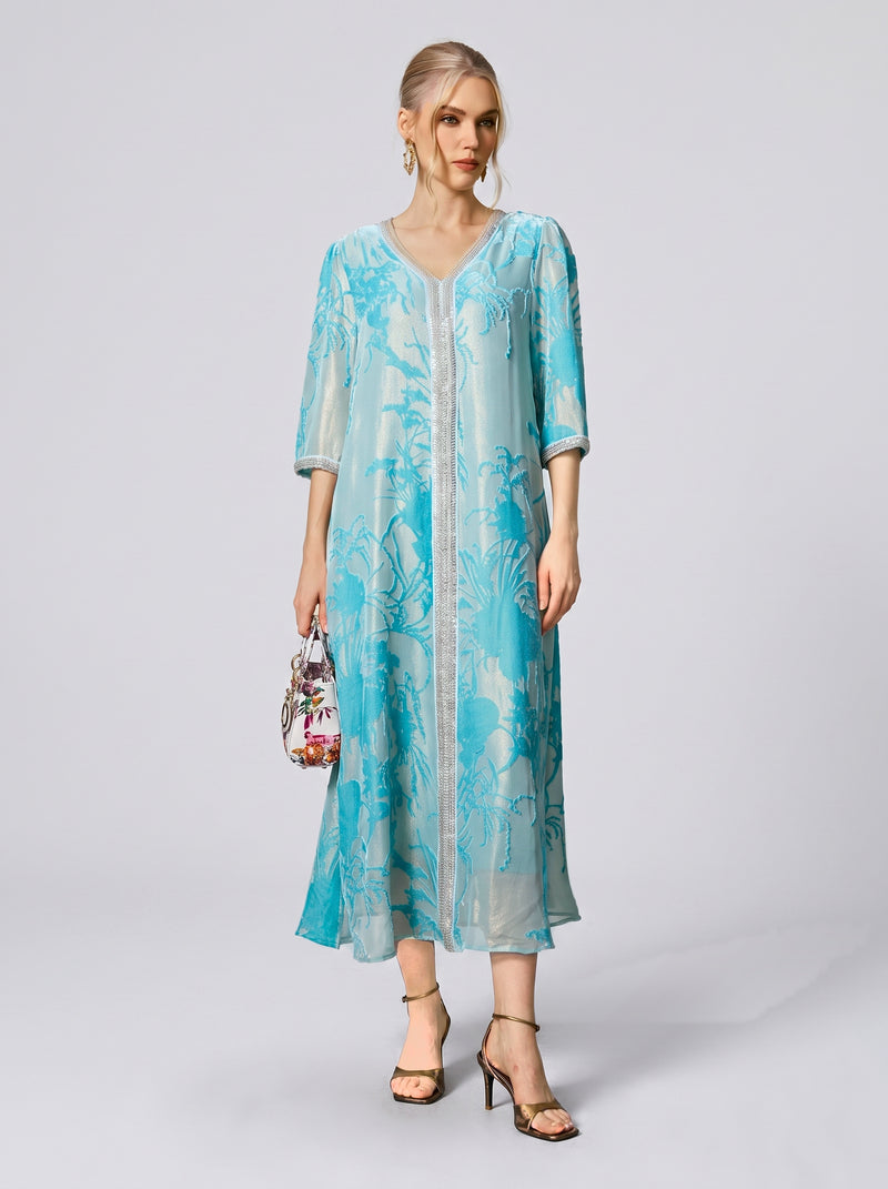 A woman wearing the Social Queen Embellished Velvet Burnout Silk Dress stands against a plain background, holding a small handbag and wearing heeled sandals.