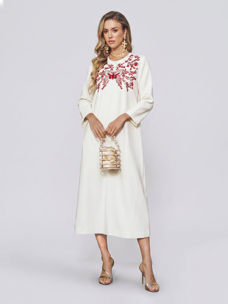 Clad in the Butterfly Embroidered A-Line Dress by Social Queen, she stands gracefully holding a small beaded handbag. Gold earrings and gold heels add subtle glamour, while her long wavy hair completes an effortlessly elegant look—perfect for a wedding guest.