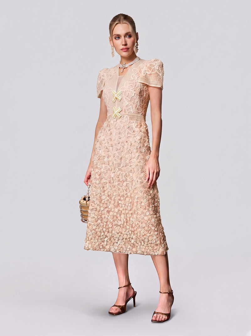 A woman wearing the Social Queen Floral Embroidered Lace Dress—a light beige, short-sleeved midi dress featuring layered lace with delicate floral embroidery—paired with a small handbag, high heels, and jewelry; an effortlessly elegant choice for a wedding guest, beautifully showcased against a plain background.