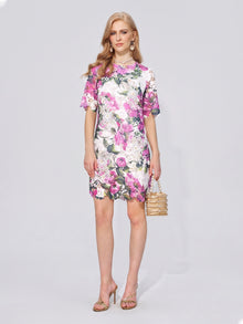 A woman stands against a plain background, wearing the Social Queen Floral Print Lace Shift Mini Dress—a short-sleeve, knee-length dress with a subtle shift silhouette—paired with heeled sandals and carrying a beaded handbag.